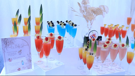 A variety of colorful cocktails arranged on a table, served in glasses with decorative elements such as fruit slices and straws.